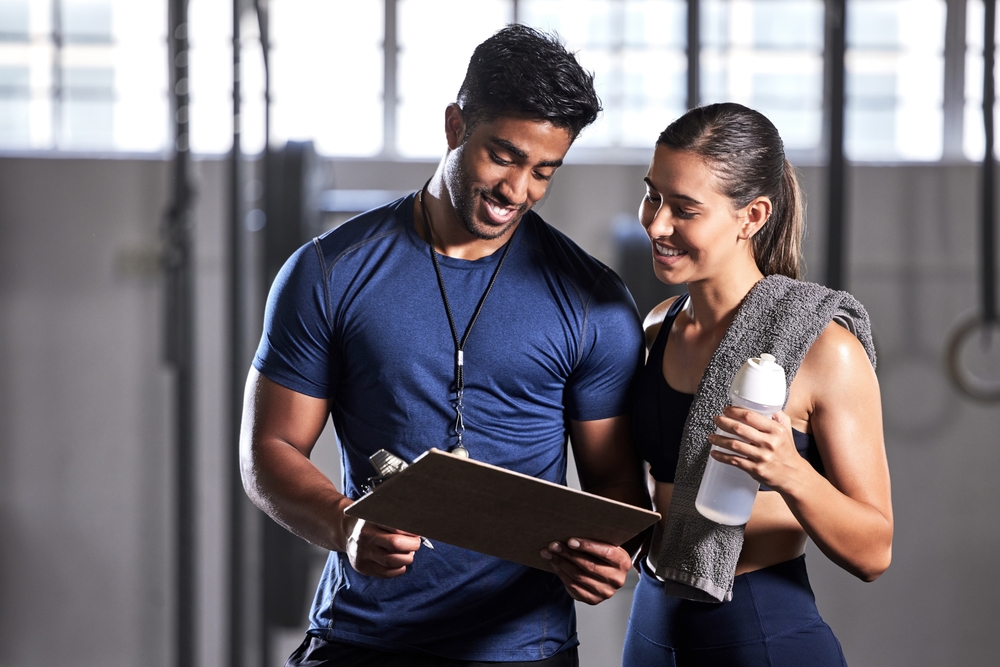 Qualified fitness instructor assessing client movement and posture during initial onboarding